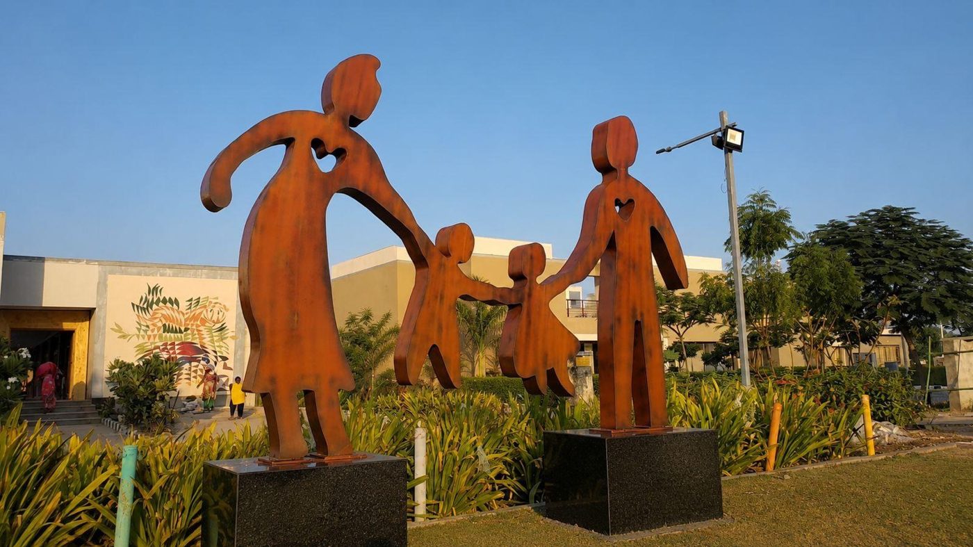 Corten steel family figures on a landscaped lawn