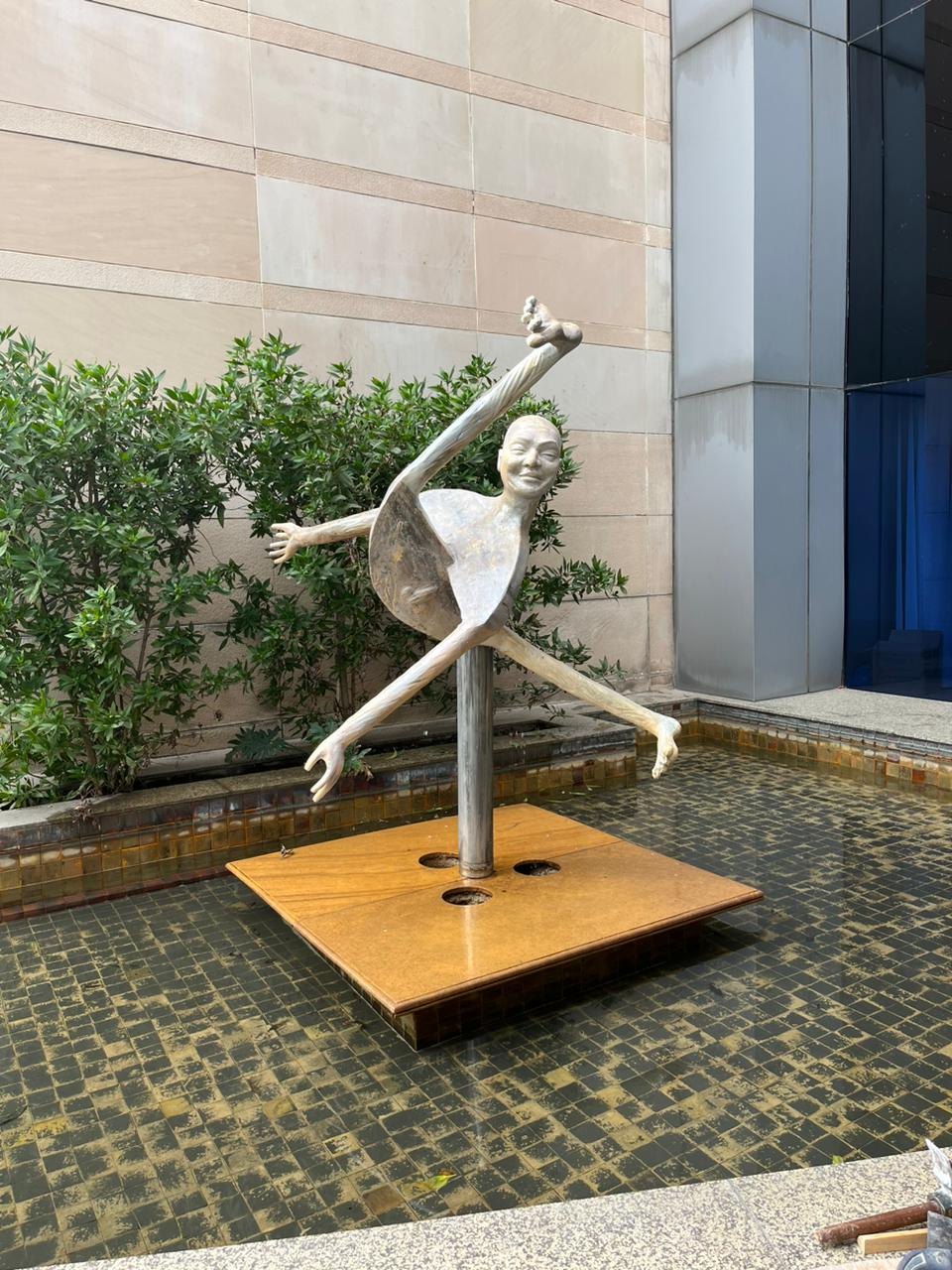 Abstract dancing figure sculpture standing in a water fountain at a corporate campus